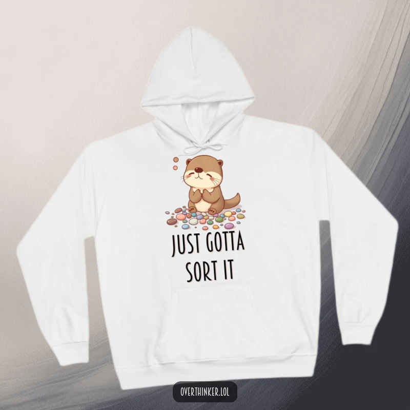 Funny hoodie showcasing an overthinking otter deeply engrossed in sorting pebbles with meticulous, humorous precision and a thoughtful expression.