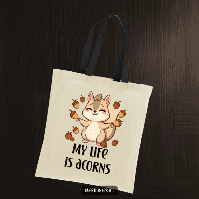 Funny tote bag with a smiling but stressed squirrel character juggling a large quantity of acorns, symbolizing busy life management.